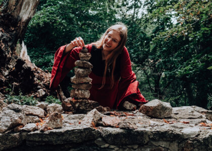 Laura Kier stapelt Steine umgeben von Bäumen